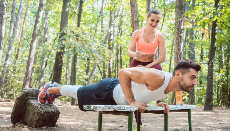 Couple doing push-ups out in nature.