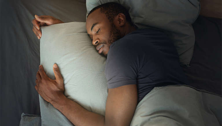 Cosy man sleeping embracing a cushion.