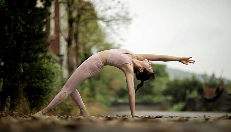 Person performing the Crab Reach pose, arching back with one hand on the ground and the other arm extended overhead.