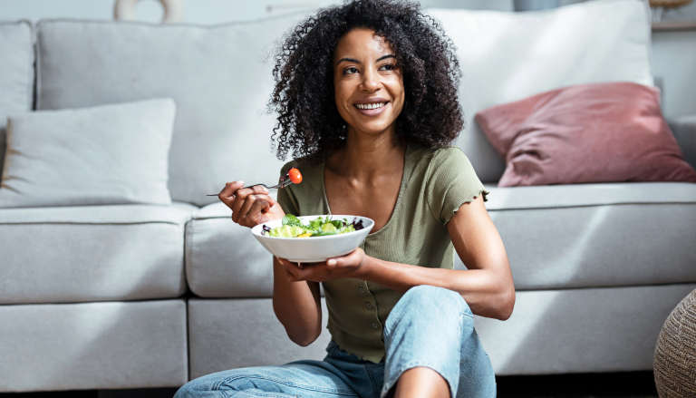 Happy black woman eating and smiling.