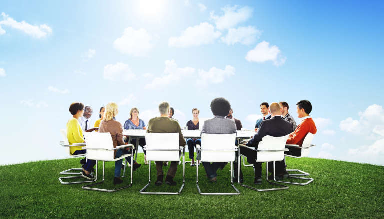 Group of people sitting round a table outside.