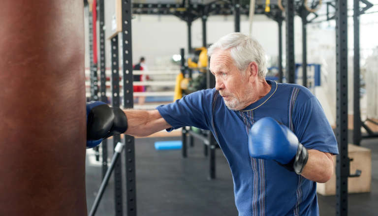 Older man boxing a punch bag.