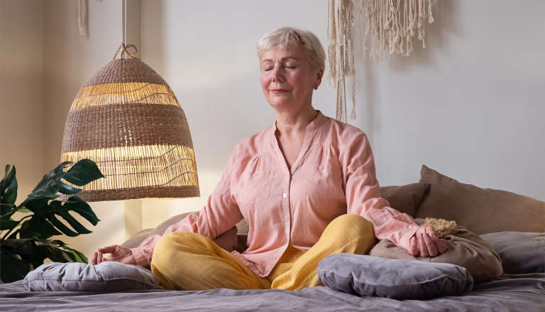 Elderly woman meditating in bed.