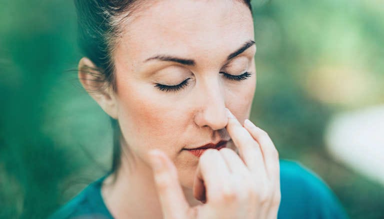 Woman practicing pranayama breathing exercise outdoors.