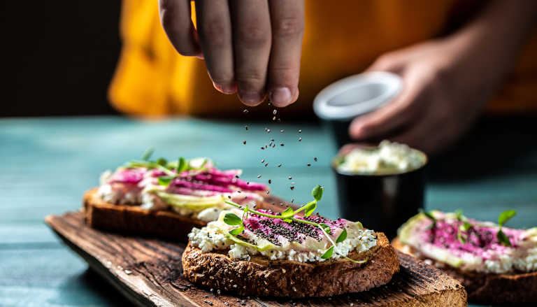 Hand sprinkling chia seeds onto toast.