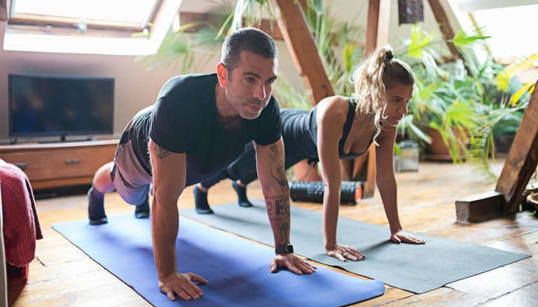 Couple practicing the Yoga plank pose indoors.